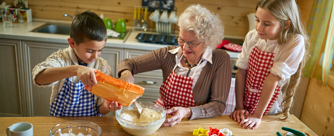 photo of grandmother making cookies with her grandchildren